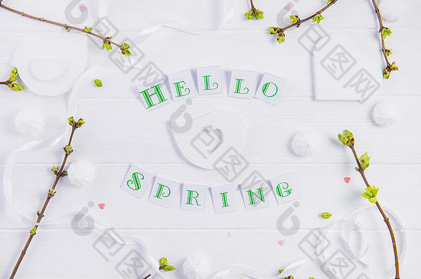 顶视图构图：Hello spring字样、嫩枝绿叶、梅伦格糖果和糖果心形、手工制作的鸟形图案