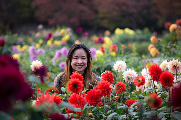 日本花园里，一位美丽的女子在红花旁摆姿势