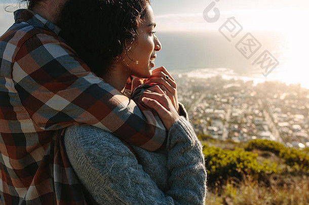 夫妇放松假期美丽的年轻的女人拥抱的男朋友站悬崖视图
