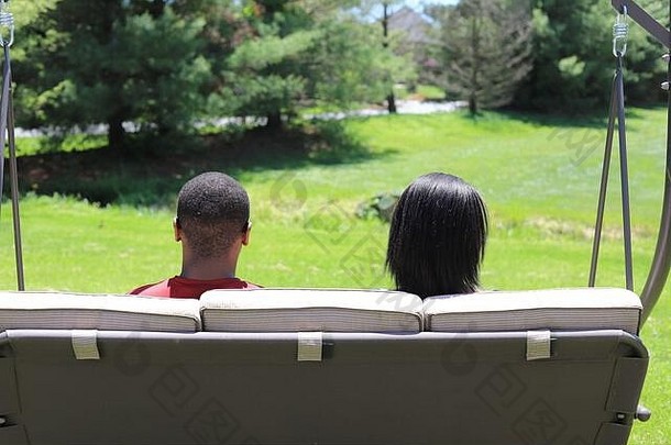 非裔美国人十几岁的夫妇坐着在户外夏天板凳上