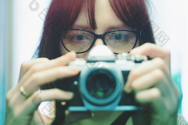 戴眼镜的年轻女孩在相机上自拍