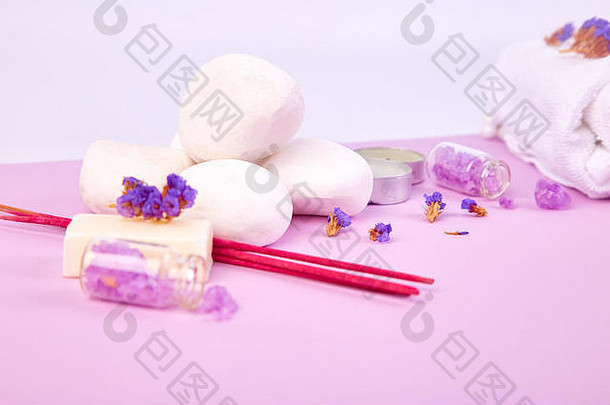 水疗概念。紫色桌子上的禅石和芳香蜡烛。采购产品美容和水疗化妆品，盐，薰衣草，毛巾。