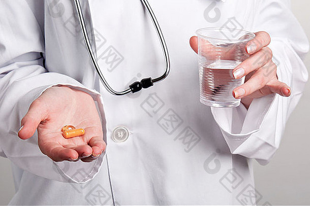 女医生一手拿着药片，另一手拿着一杯水