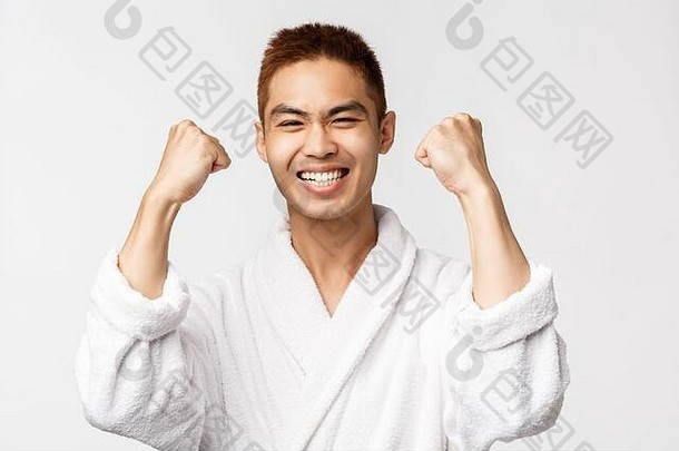 美容、spa和休闲概念。心满意足的亚洲男子在浴衣上拳打脚踢，喜形于色，笑容可掬，高兴得像<strong>中奖</strong>者，实现了目标