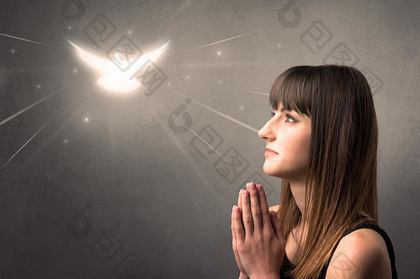 一名年轻女子在<strong>灰色</strong>背景上祈祷，头顶上有一只闪闪发光的小鸟