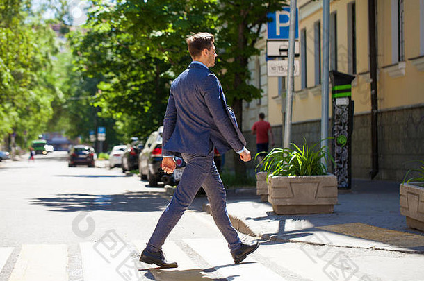 一个穿着西装的年轻人在人行横道上<strong>横穿马路</strong>的全貌