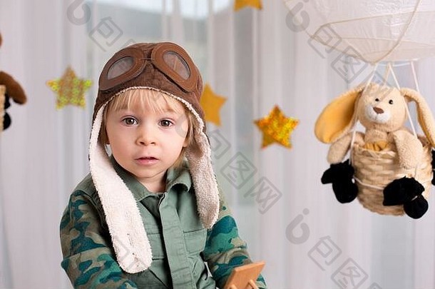可爱的蹒跚学步的男孩，玩飞机和泰迪熊，用玩具装饰气球