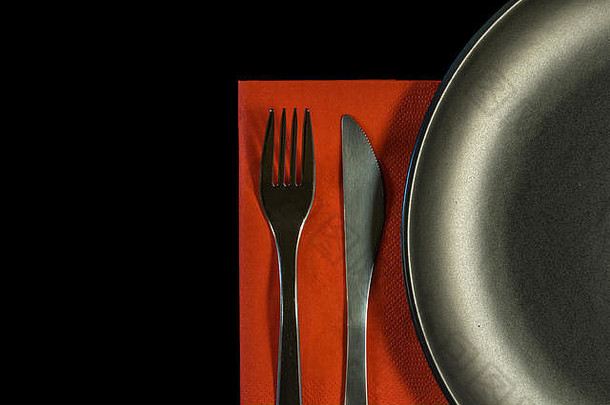 金属叉，<strong>红</strong>色餐巾上的刀和黑色背景上的盘子。带复印空间的<strong>不锈钢</strong>刀叉俯视图。