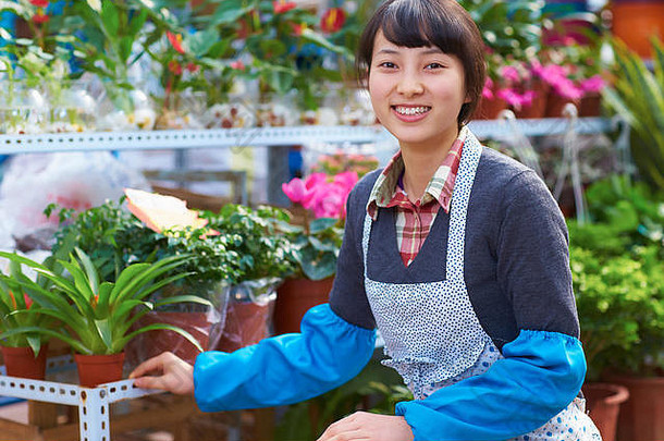 一位美丽的中国妇女在花店对着镜头微笑
