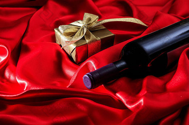 情人节的概念。红丝织物上的红酒瓶和礼品盒