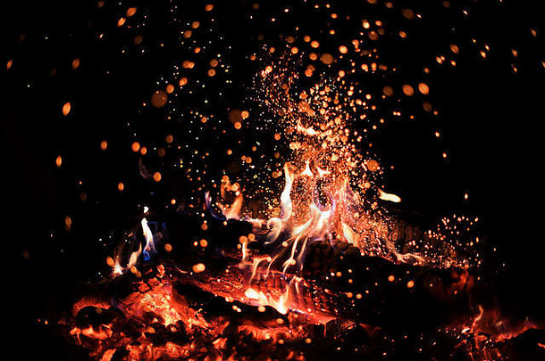 夜晚营火中明亮的橙色和红色火花的背景