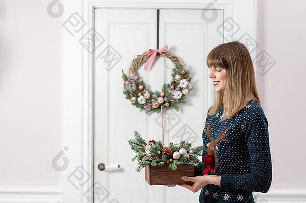 一个年轻的<strong>女人</strong>拿着一个圣诞木箱，上面有枞树的树枝，准备过节。新年庆典。