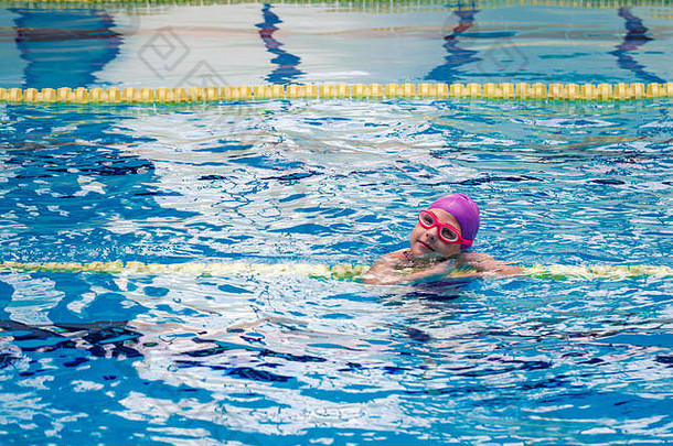 穿着紫色泳衣的可爱小女孩在游泳池里游泳