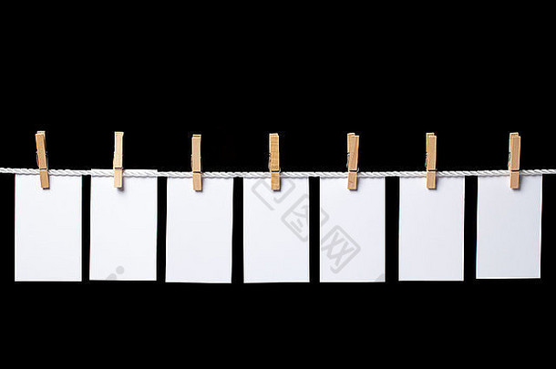 七张白色的小纸片，用衣夹挂在绳子上。这部作品是在黑色背景上独立创作的。里拉酒店