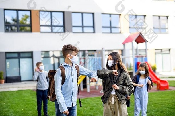 孩子们戴着口罩回学校后，COVID-19锁定，打招呼。