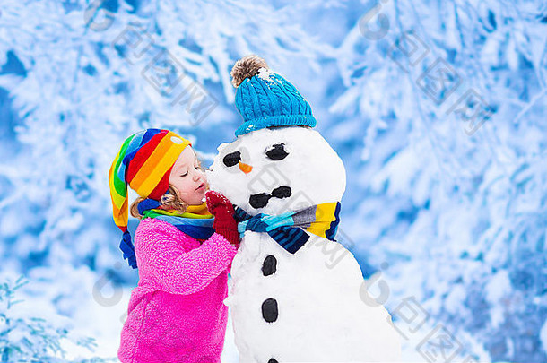 有趣的蹒跚学步的女孩色彩斑斓的他温暖的外套玩雪男人。孩子们玩在户外冬天
