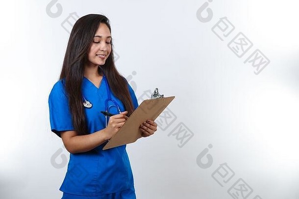 一个穿着蓝色衣服的漂亮护士在她的剪贴板上写笔记。