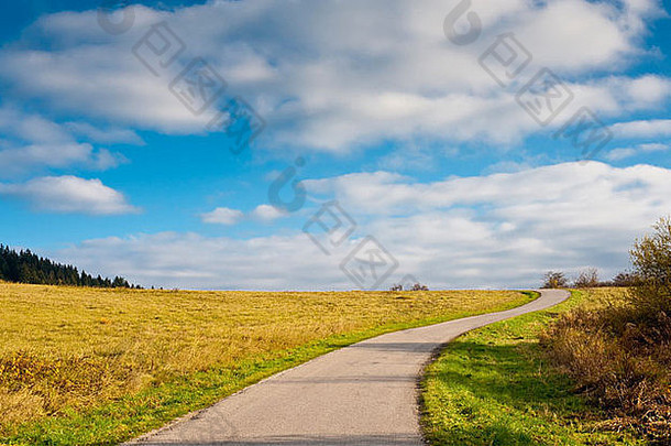在秋天的乡间，道路和地平线发生了变化，草地上布满了云朵