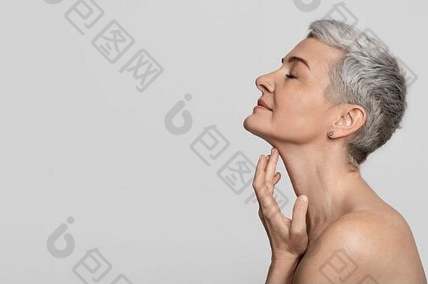 抗衰老治疗美丽的中年女人触碰软皮肤脖子