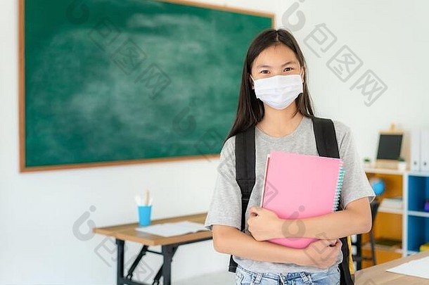 亚洲<strong>小学</strong>生带着背包和书籍，戴着口罩，在教室里防止新冠病毒19型的爆发，回到学校后重新<strong>开学</strong>