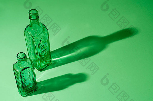 两个绿色瓶子在绿色背景上投下长长的阴影