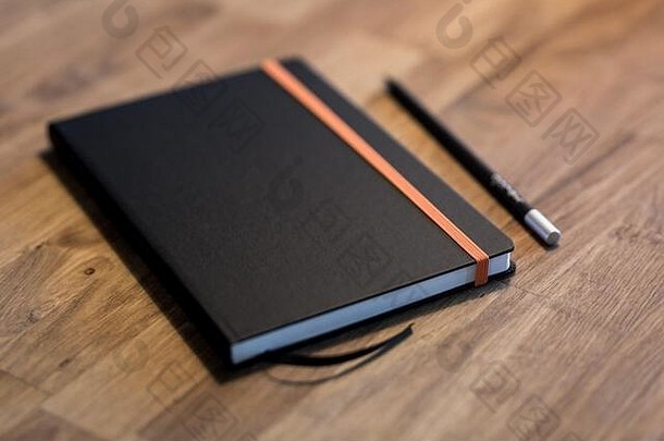复古木桌上的黑色商务笔记本和普通铅笔