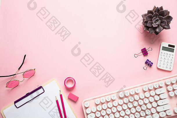 女办公桌。粉色背景下的电脑键盘和文具，复印空间