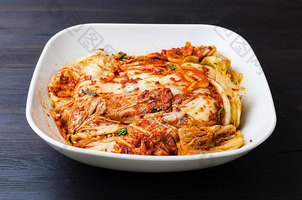 <strong>韩国料理</strong>-泡菜开胃菜（辣味纳帕卷心菜），装在深棕色木板上的白碗中