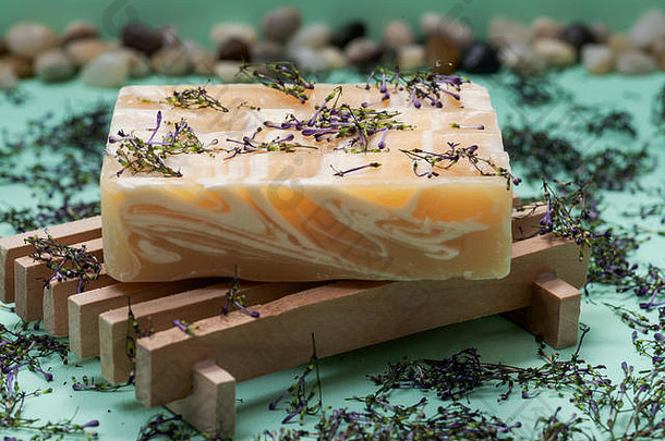 木制香皂架，配有手工制作的超保湿杏仁香味山羊奶条香皂，绿色背景上点缀着花朵和五彩纸屑。