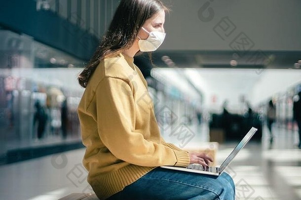 一位年轻女子在一座空荡荡的商业中心大楼里用笔记本电脑工作