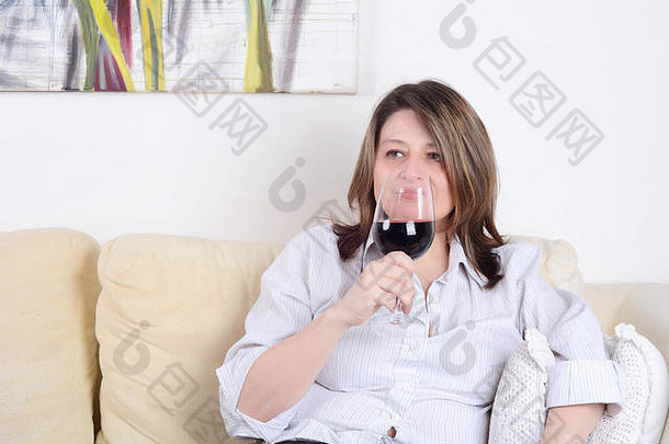 一位美丽女子的画像，她在沙发上悠闲地喝着一杯酒。在室内