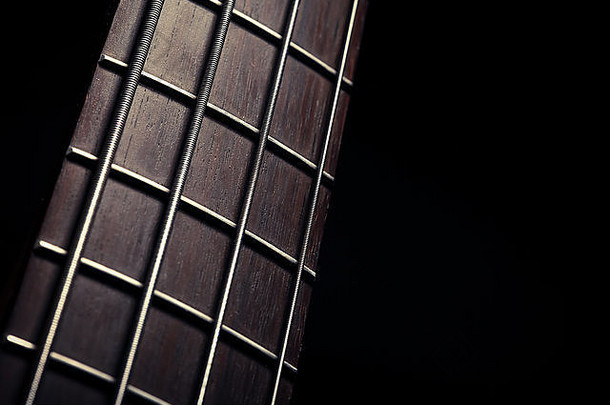 黑色背景上低音吉他的fret板细节。