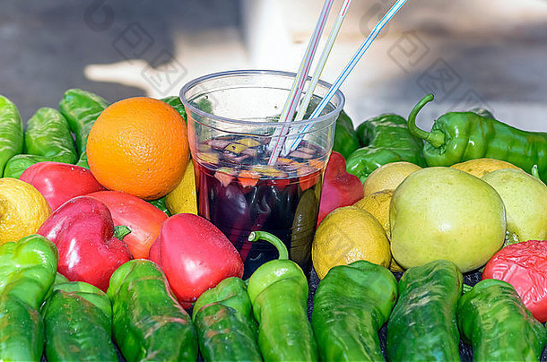 带桑格里亚的塑料杯，典型的西班牙饮料。在附近，有一些水果和蔬菜。