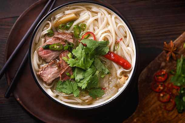 越南传统汤火锅配牛肉和新鲜芫荽，深色木质背景
