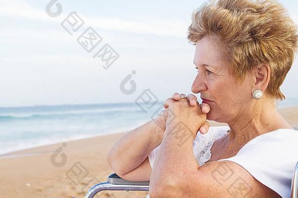 体贴的残疾老人坐在沙滩上的轮椅上