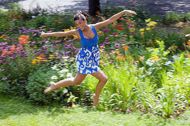 年轻的亚洲女子在花园里欢蹦乱跳