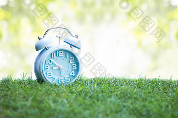 绿色草地上可爱的蓝色闹钟，白色背景
