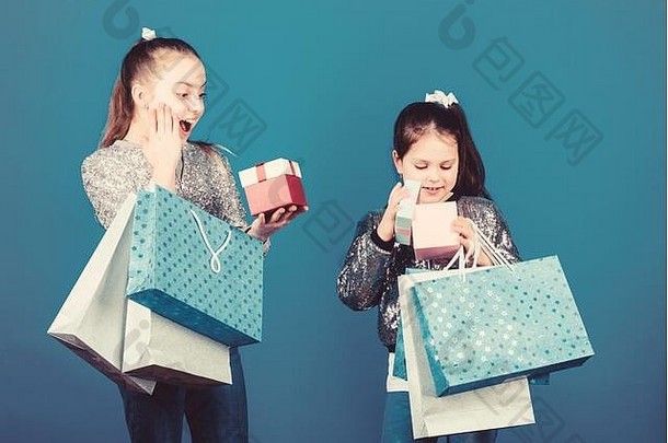 购物日。孩子们把包裹捆起来。儿童时尚。带蓝色背景购物袋的女孩姐妹朋友。交付给您的所有产品。购物和购买。黑色星期五。销售和折扣。