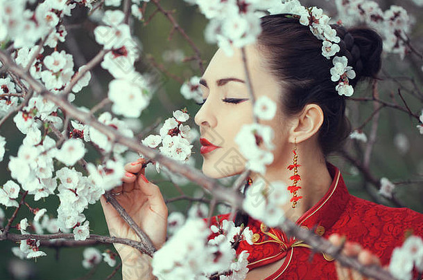 有吸引力的亚洲女人闻花开花树在户外花园