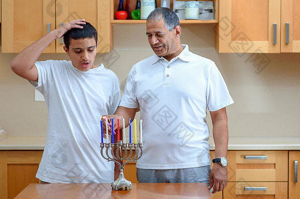 幸福家庭点燃蜡烛，共同庆祝犹太节日光明节。犹太父亲和十几岁的儿子或祖父与孙子在烛台上点燃光明节蜡烛