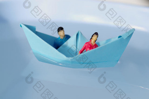 一对夫妇坐在纸船里，在水中航行