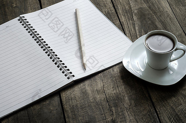 打开桌上一个空白的白色笔记本，钢笔和一杯咖啡，收起