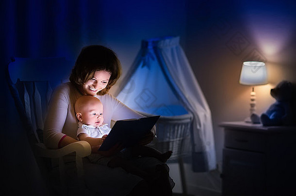 妈妈。婴儿阅读书黑暗卧室妈妈孩子读书床上时间家庭晚上