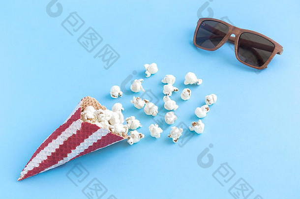 爆米花配冰淇淋筒和3d眼镜，柔和的蓝色背景，简约的电影创意理念