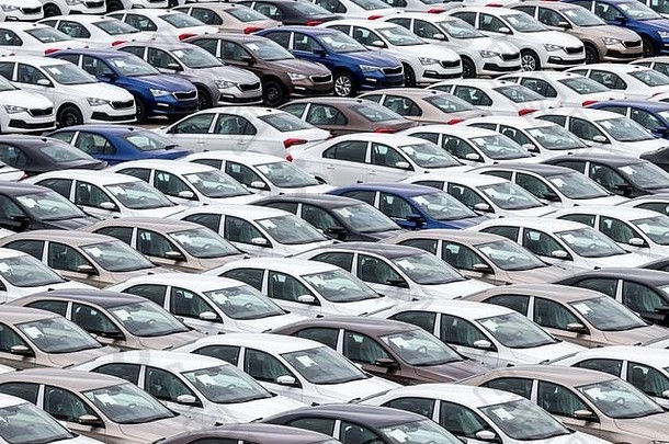 一排新车停在一家汽车厂的配送中心。露天停车场俯视图。