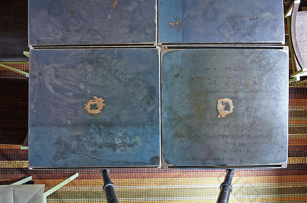 从上方和摄影师三脚架看到的粗糙和划伤的金属桌视图