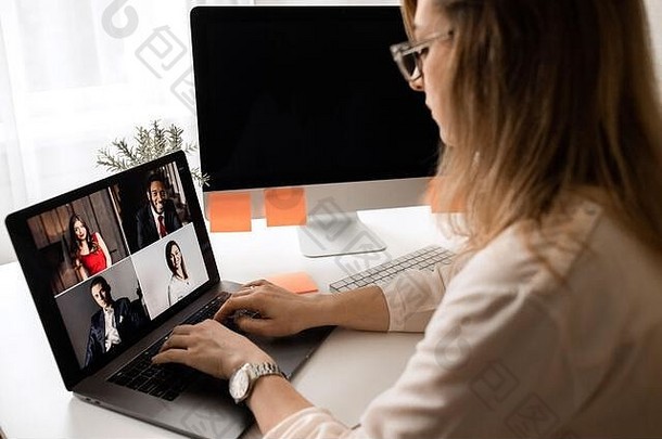 在笔记本电脑上使用网络摄像头会议的女商人演讲的后视图