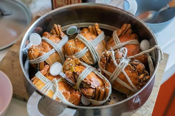 蒸<strong>大闸蟹</strong>。把蟹拴在家里煮的蒸锅里。