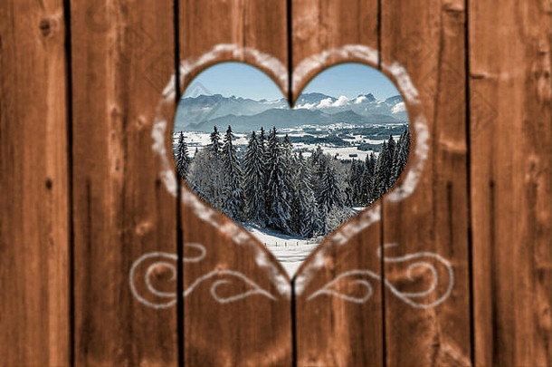 透过木墙上雕刻的心形，眺望美丽的雪景