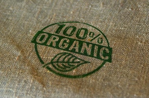 有机100%邮票印在亚麻布袋上。生态、生物、无转基因、天然和健康饮食概念。